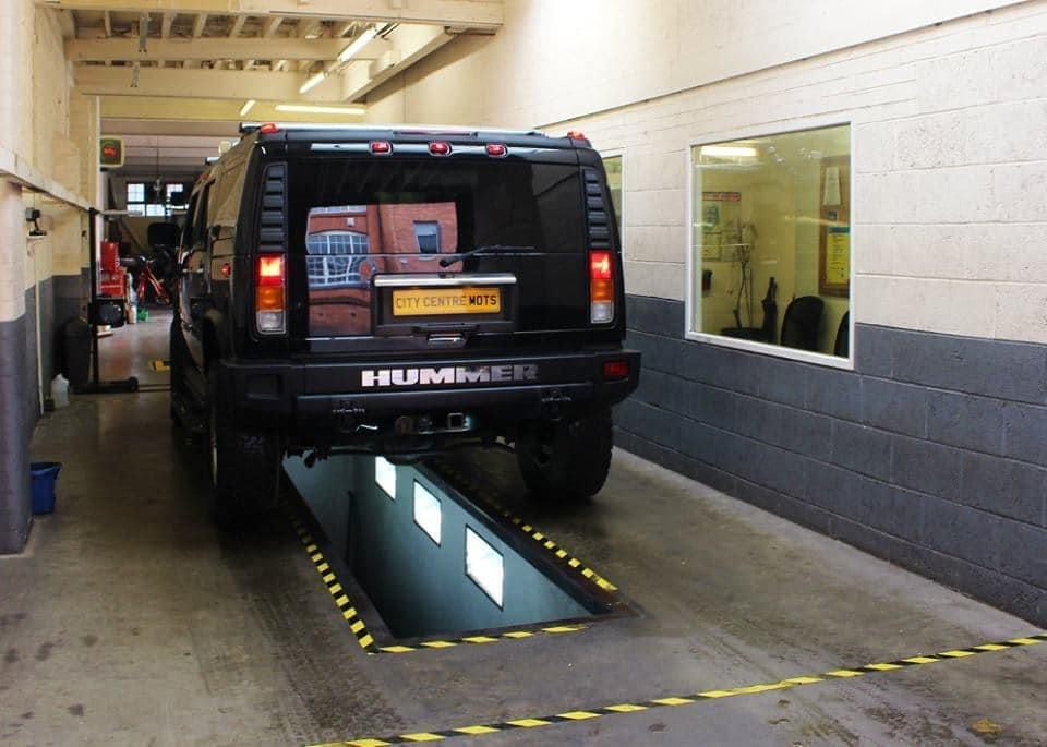 A vehicle raised on the MOT lift ramp inside the test bay at City Centre MOTs